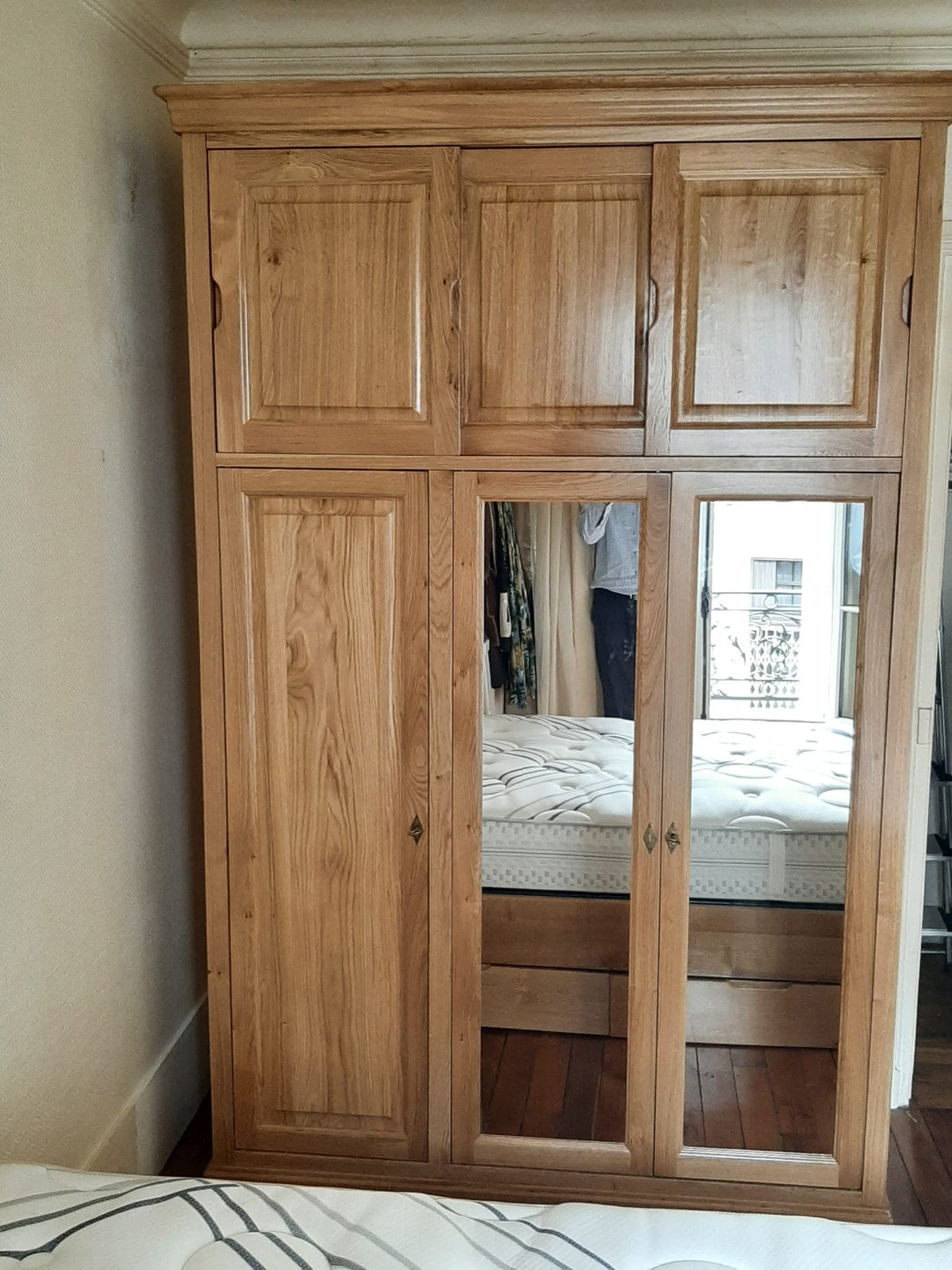 Armoire de chambre en chêne massif à nœuds apparents, surmeuble à trois portes, trois portes basses dont deux à miroir, entrées de serrure en losange et corniche moulurée