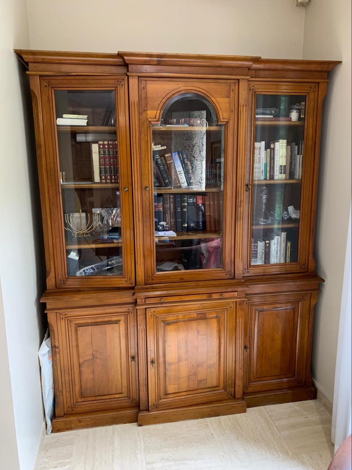 Bibliothèque-vitrine deux corps en merisier massif à avant-corps central : trois portes vitrées dont une à cintre mouluré, rosaces sculptées aux angles des cadres, pilastres cannelés et trois portes à panneaux en partie basse
