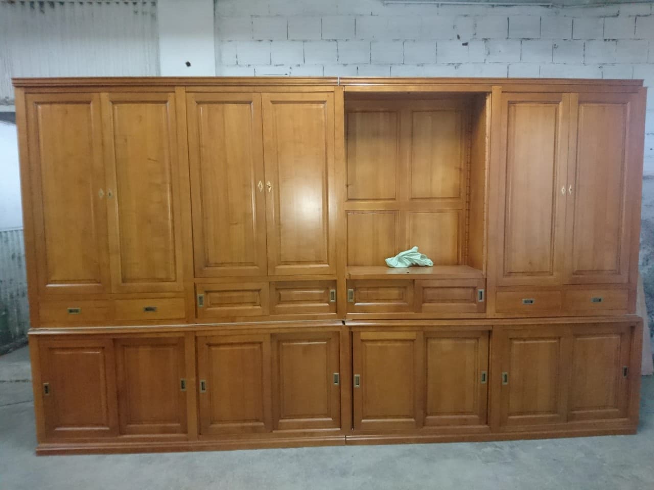 Bibliothèque-armoire de 4 mètres en merisier massif : trois groupes de hautes portes à panneaux moulurés, niche centrale ouverte à fond menuisé, rangée continue de tiroirs et buffet bas fermé