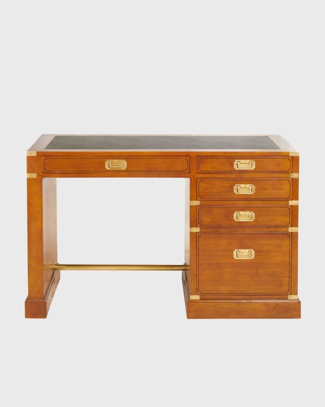 Bureau anglais de style campagne militaire : poignées de laiton encastrées, cornières de laiton aux angles, sous-main de cuir vert, caisson de quatre tiroirs, piètement à panneau plein et barre de laiton en repose-pied