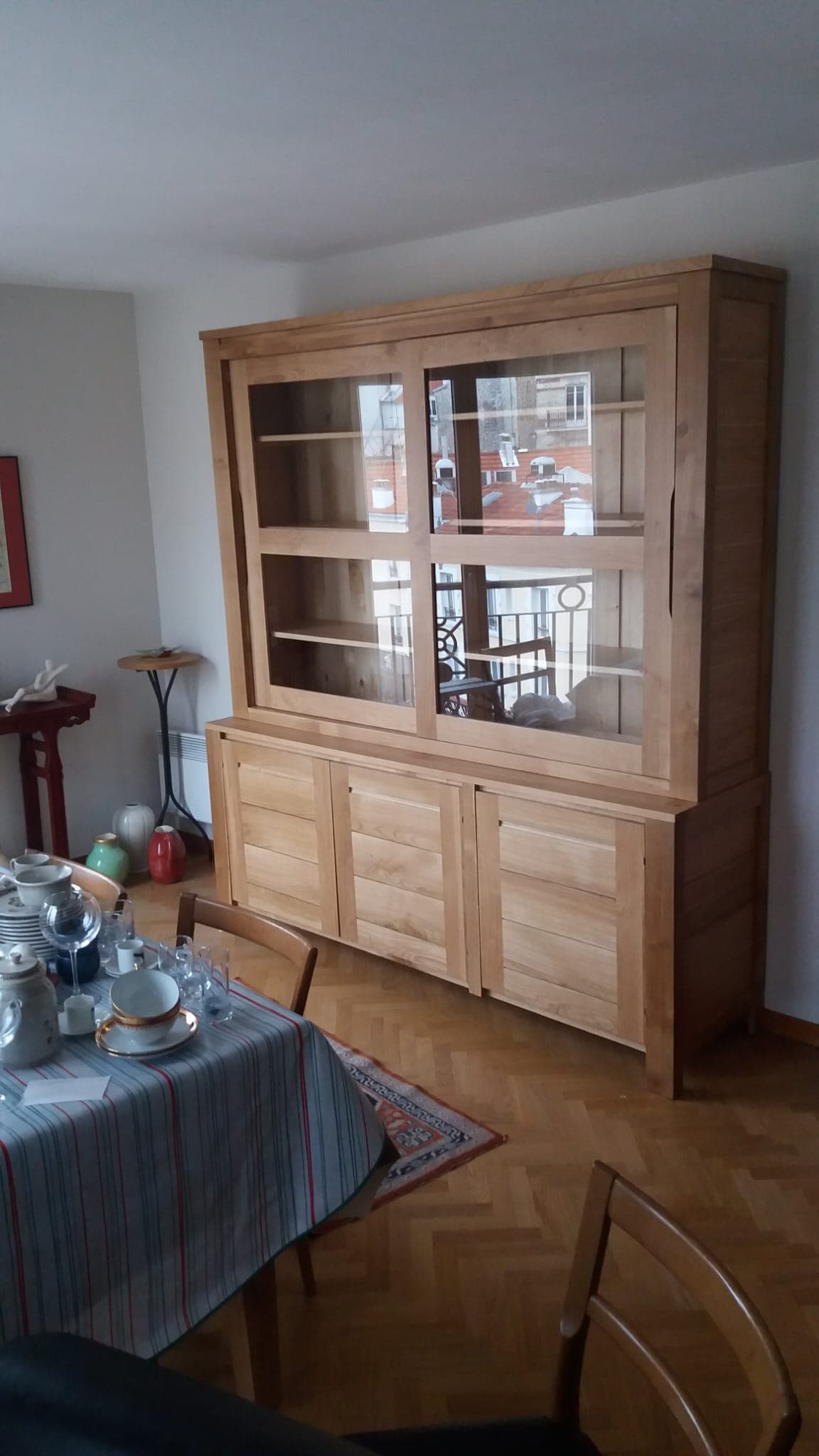Bibliothèque-vitrine deux corps en chêne massif à portes coulissantes, installée dans une salle à manger parisienne