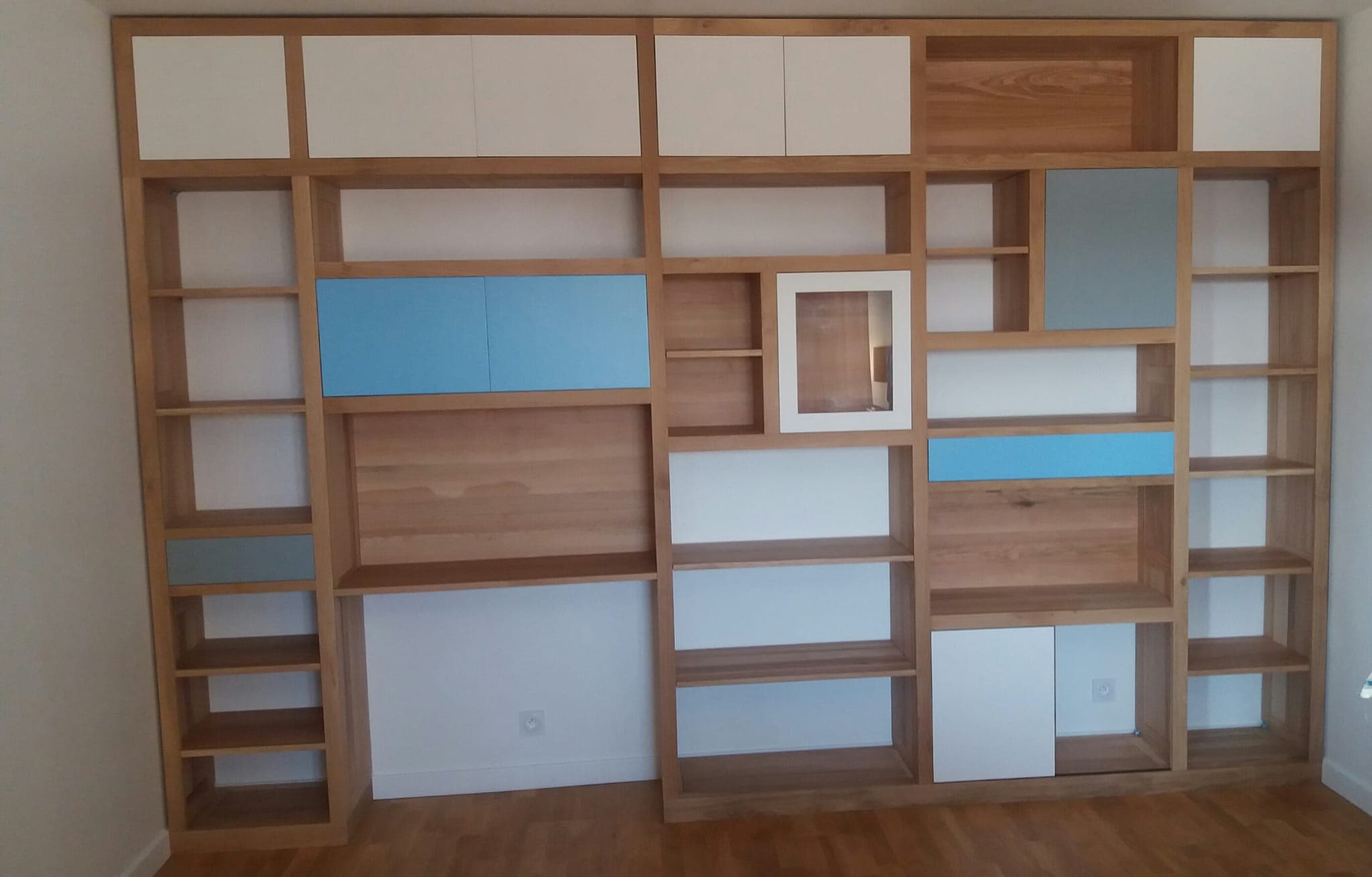 Bibliothèque sur mesure toute hauteur en chêne avec niches ouvertes et façades laquées blanc et bleu