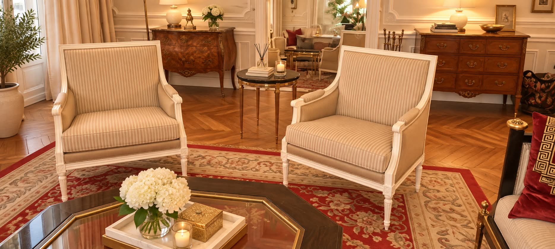 Paire de bergères Louis XVI laquées blanc et tissu rayé beige, face à face autour d’une table basse dans un salon à parquet en point de Hongrie