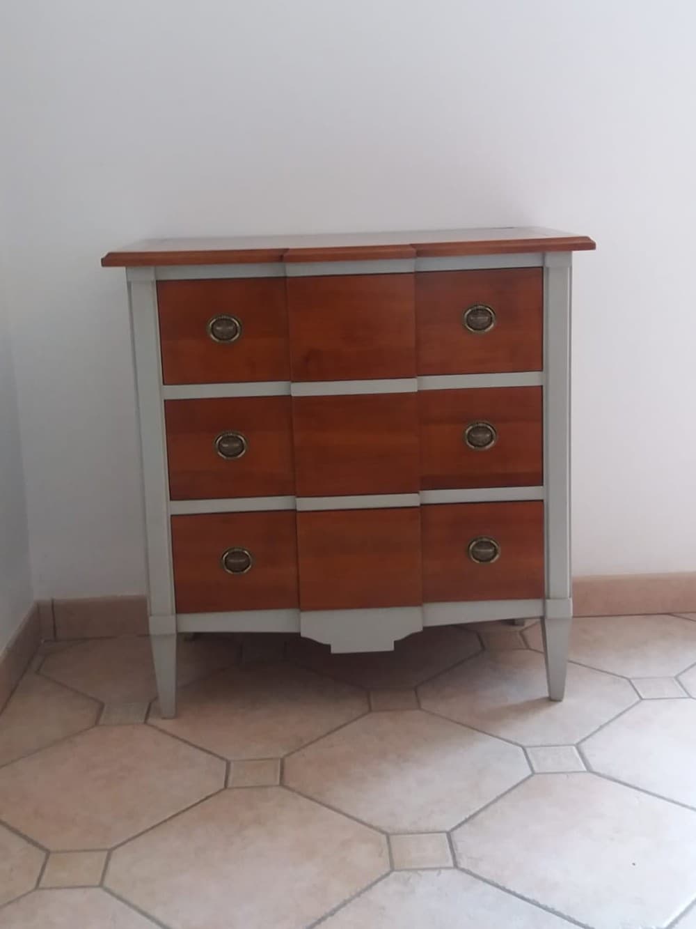 Commode Directoire à trois rangs de tiroirs à ressaut central, façades et plateau en merisier massif, bâti, tablier découpé et pieds gaine laqués gris, poignées à anneau ovale en laiton