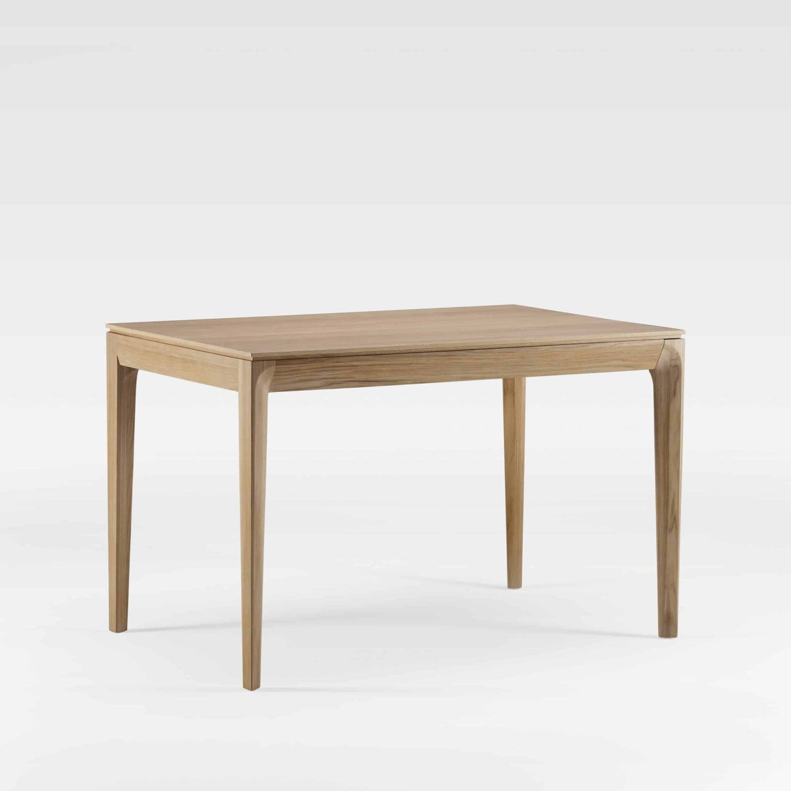 Table de repas rectangulaire en chêne massif clair, piètement fuselé raccordé à la ceinture par une courbe douce, plateau à chant biseauté et finition mate